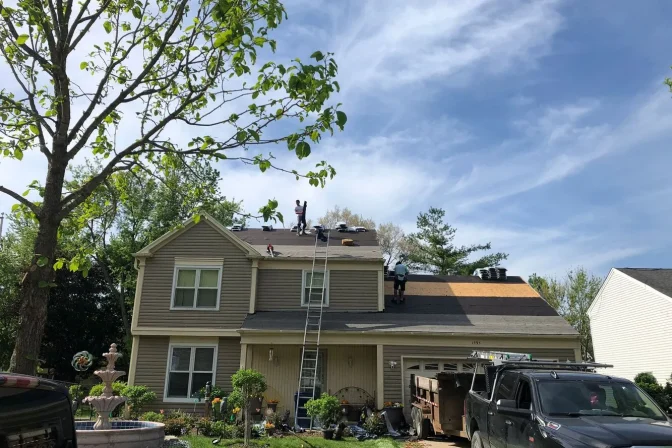 full house exterior with roofing contractor team working on the shingle roof