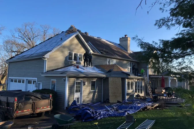 exterior of the house with roofing contractor team during roof replacement