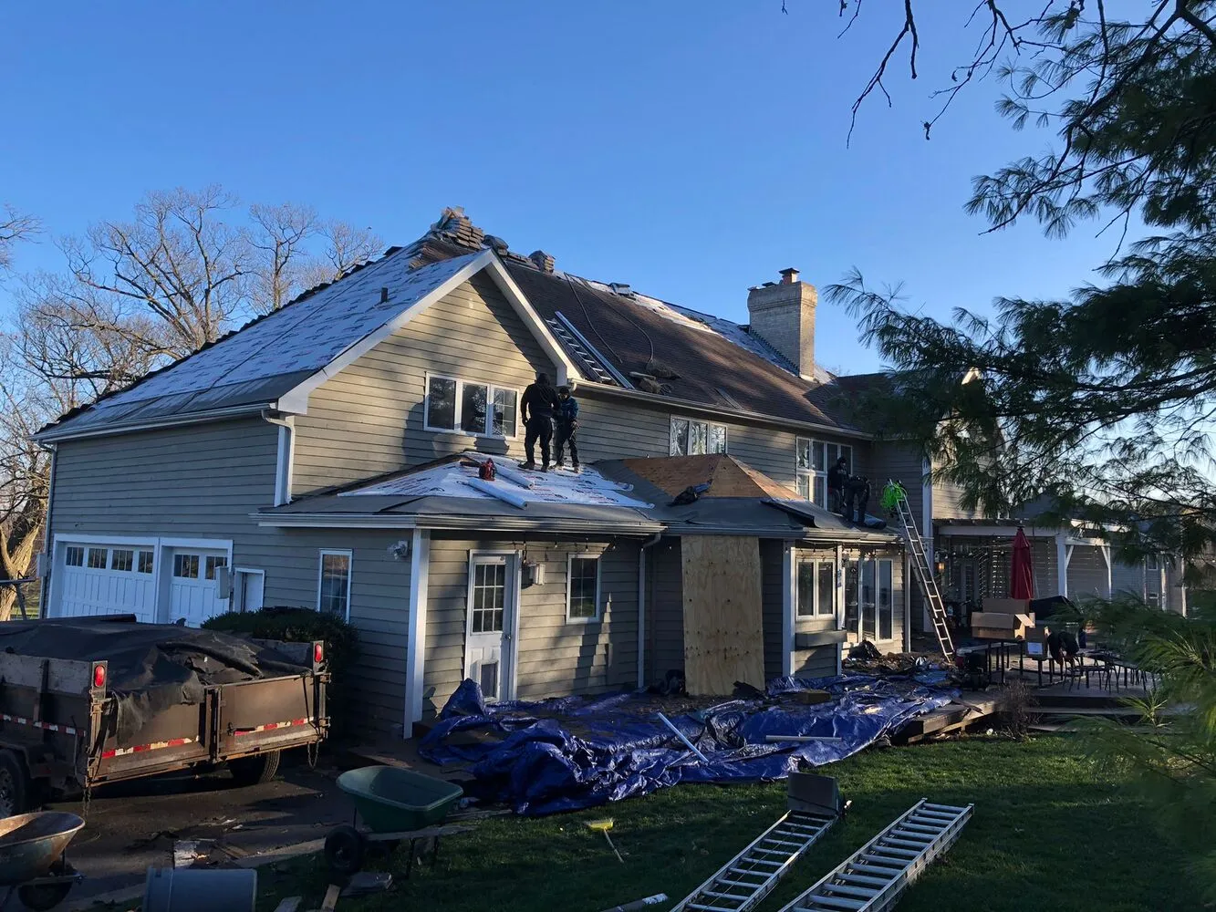exterior of the house with roofing contractor team during roof replacement