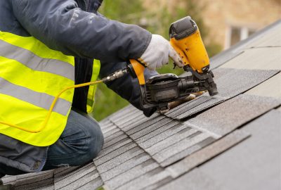 Contractor on the roof of a house in Chicago installs roofing with specialized tools